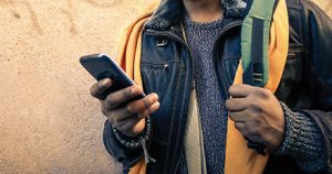 Person im Anschnitt abgebildet, mit Smartphone in der Hand.