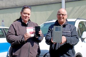 Zwei Überwachungskräfte der Stadt Detmold zeigen die alte und neue Technik: Bisher mussten die Verwarnungen über ein schweres Gerät inklusive Drucker ausgestellt werden (rechts)