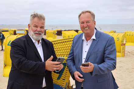 Cuxhavens Kurdirektor Olaf Raffel (links) und Oberbürgermeister Uwe Santjer testen das neue kostenlose WLAN am Strand.