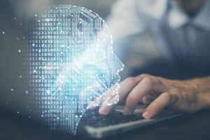 Hände tippen auf Computer-Keyboard (leicht unscharf), davor gerenderter Kopfumriss aus helltürkisen Punkten und Linien