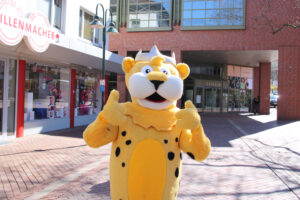 Ein Mensch als Leo der Leopard verkleidet, das Stadtmaskottchen von Georgsmarienhütte, hält beide Daumen hoch.