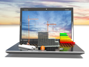 Auf dem Bildschirm eines aufgeklappten Laptops sind zwei und den Himmel ragende Kräne zu sehen, auf der Tastatur liegen eingerollte Baupläne, ein Modell des geplanten Gebäudes und Balken, welche die Energieeffizienz anzeigen.