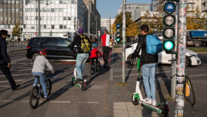 Zweiräder, autos und Fußgänger an einer großstaädtischen Kreuzung.