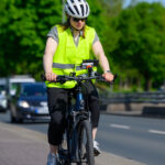Eine Frau fährt mit einem Fahrrad eine Straße entlang, am Lenker ist eine Kamera befestigt.