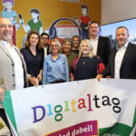 Mehrere Personen stehen in einem Raum und halten ein Banner in den Händen.