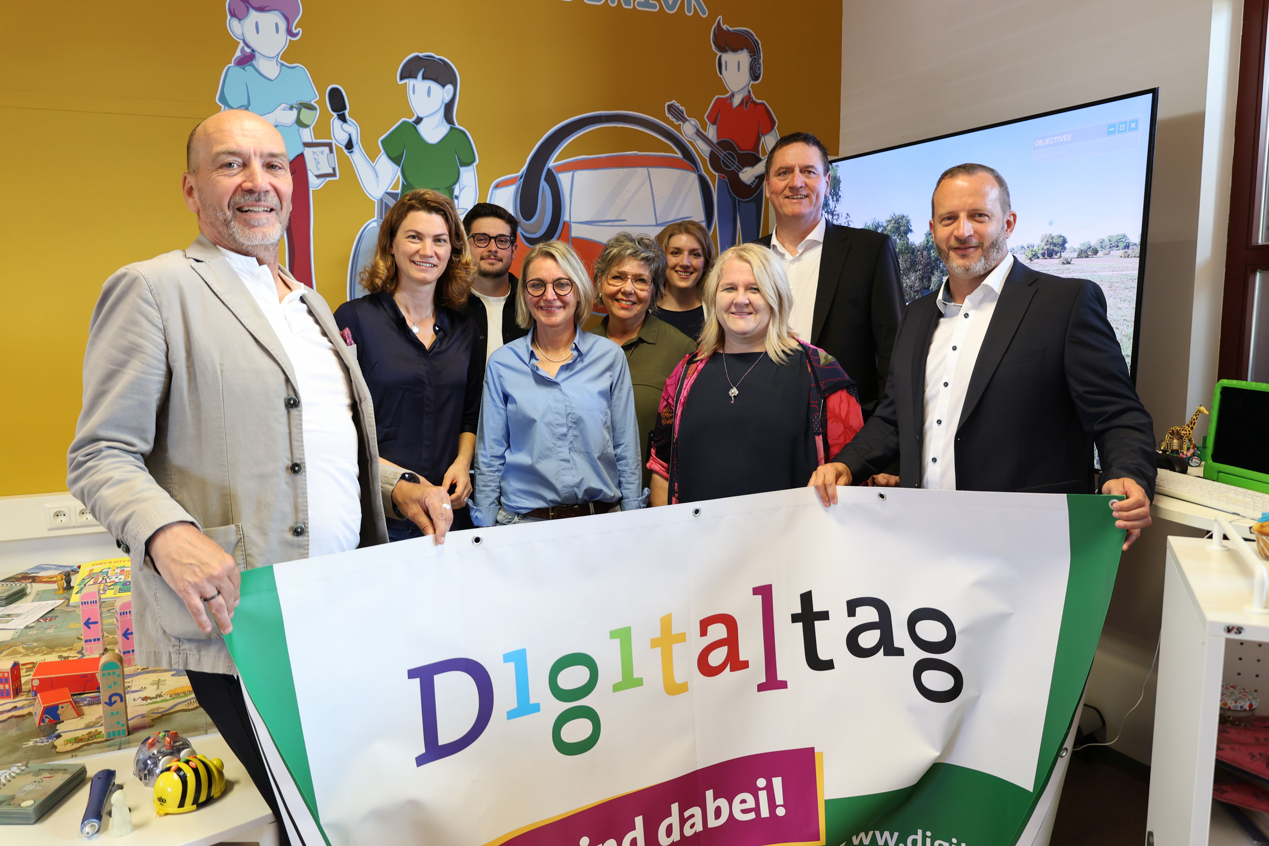 Mehrere Personen stehen in einem Raum und halten ein Banner in den Händen.