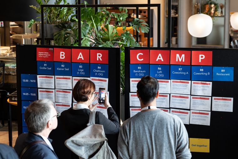 Kongressteilnehmer informieren sich an einer Infotafel über mögliche Barcamp-Themensessions.