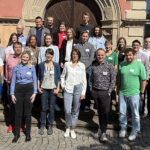 Mehrere Personen stehen vor dem Eingang eines Gebäudes.