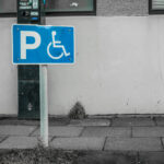 Schild für Behindertenparkplatz vor einer Häuserwand