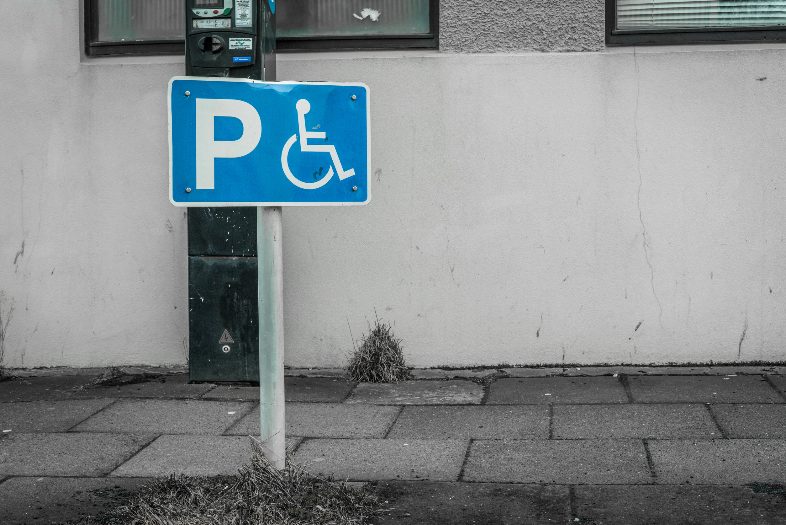 Schild für Behindertenparkplatz vor einer Häuserwand