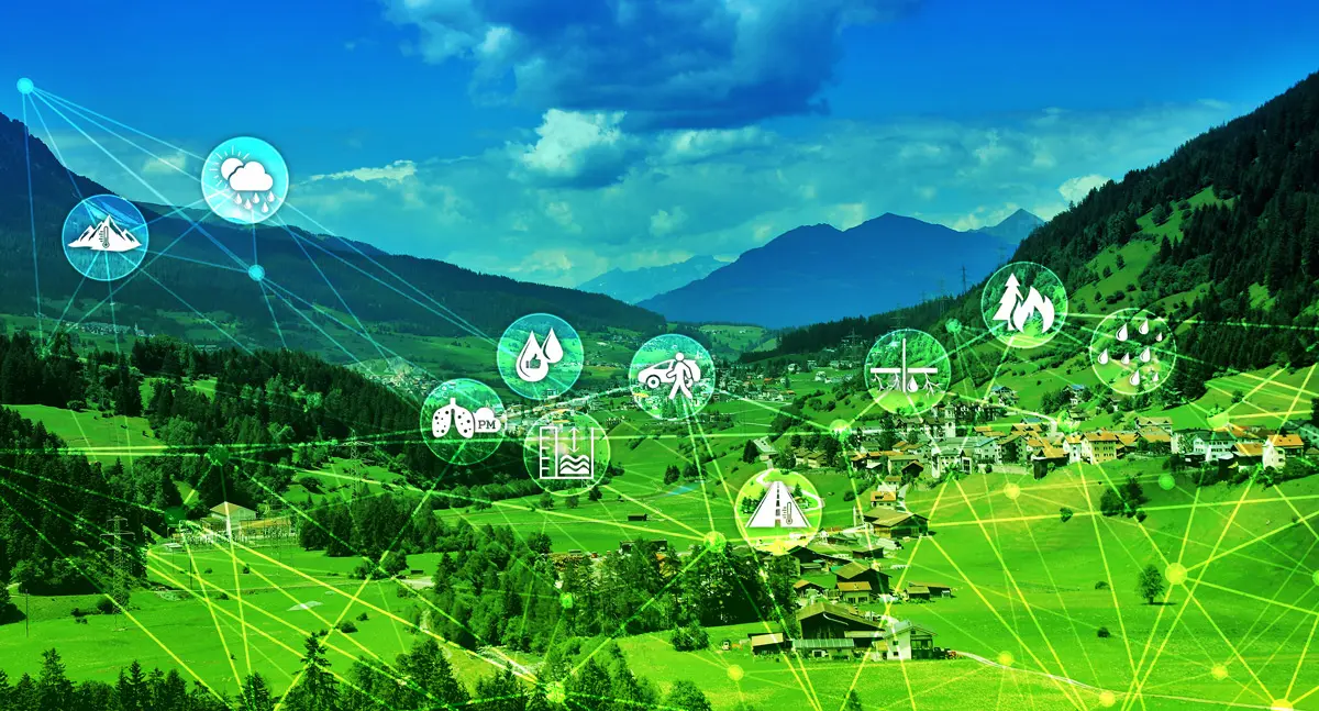 Grafik zeigt eine ländliche Landschaft umgeben von Bergen, darüber schweben unterschiedliche Symbole zu Temperatur, Niederschlag, Mobilität, Straßen und ähnliches die miteinander verbunden sind.