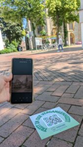 Detailaufnahme eines auf Pflastersteine applizierten QR-Codes, im Hintergrund ein historisches Gebäude.