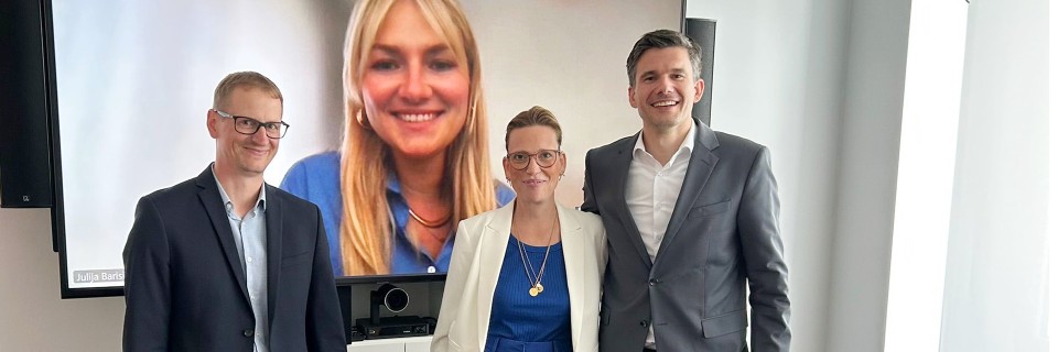 drei Personen vor einem Bildschirm, Frauengesicht auf Bildschirm