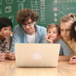 Lehrer und Schüler sitzen vor einem Laptop