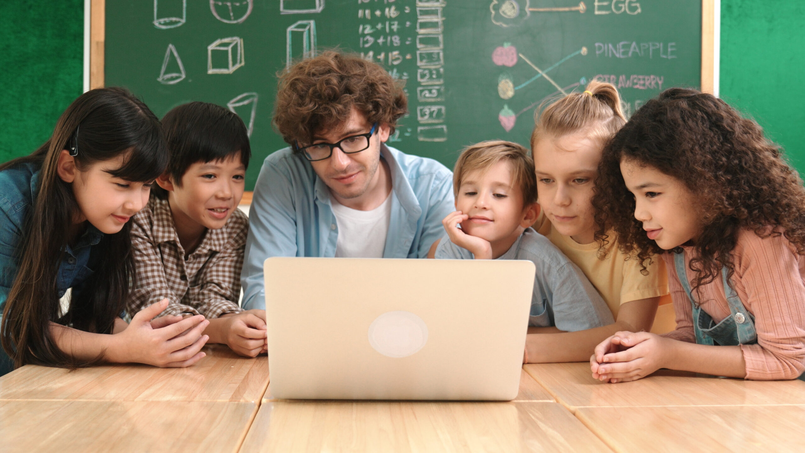 Lehrer und Schüler sitzen vor einem Laptop