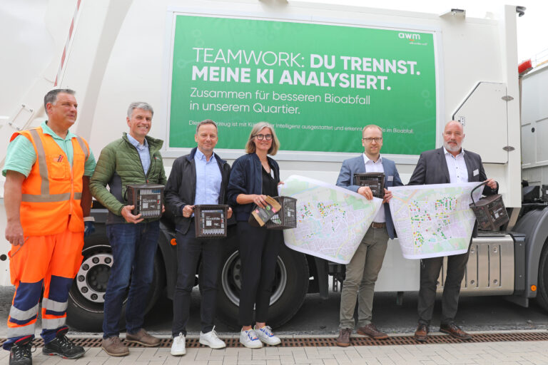 Mehrere Personen stehen vor einem Abfallsammelfahrzeug, das per Schriftzug auf den KI-Einsatz zur Abfalltrennung hinweist.