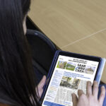 Mitteilungsblatt der Stadt Saarbrücken auf einem Tablet, Person mit langen Haaren hält es in der Han und liest darauf