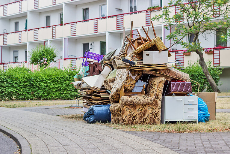 Ordentlich zusammengestellter Sperrmüll stapelt sich vor einem Mehrfamilienhaus.