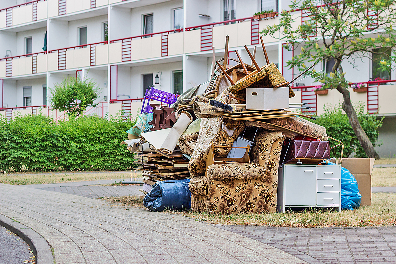 Ordentlich zusammengestellter Sperrmüll stapelt sich vor einem Mehrfamilienhaus.