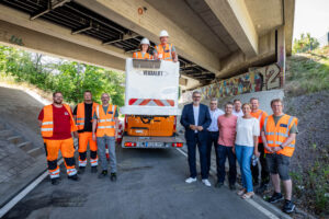 Mehere Personen stehen unter einer Brücke versammelt.