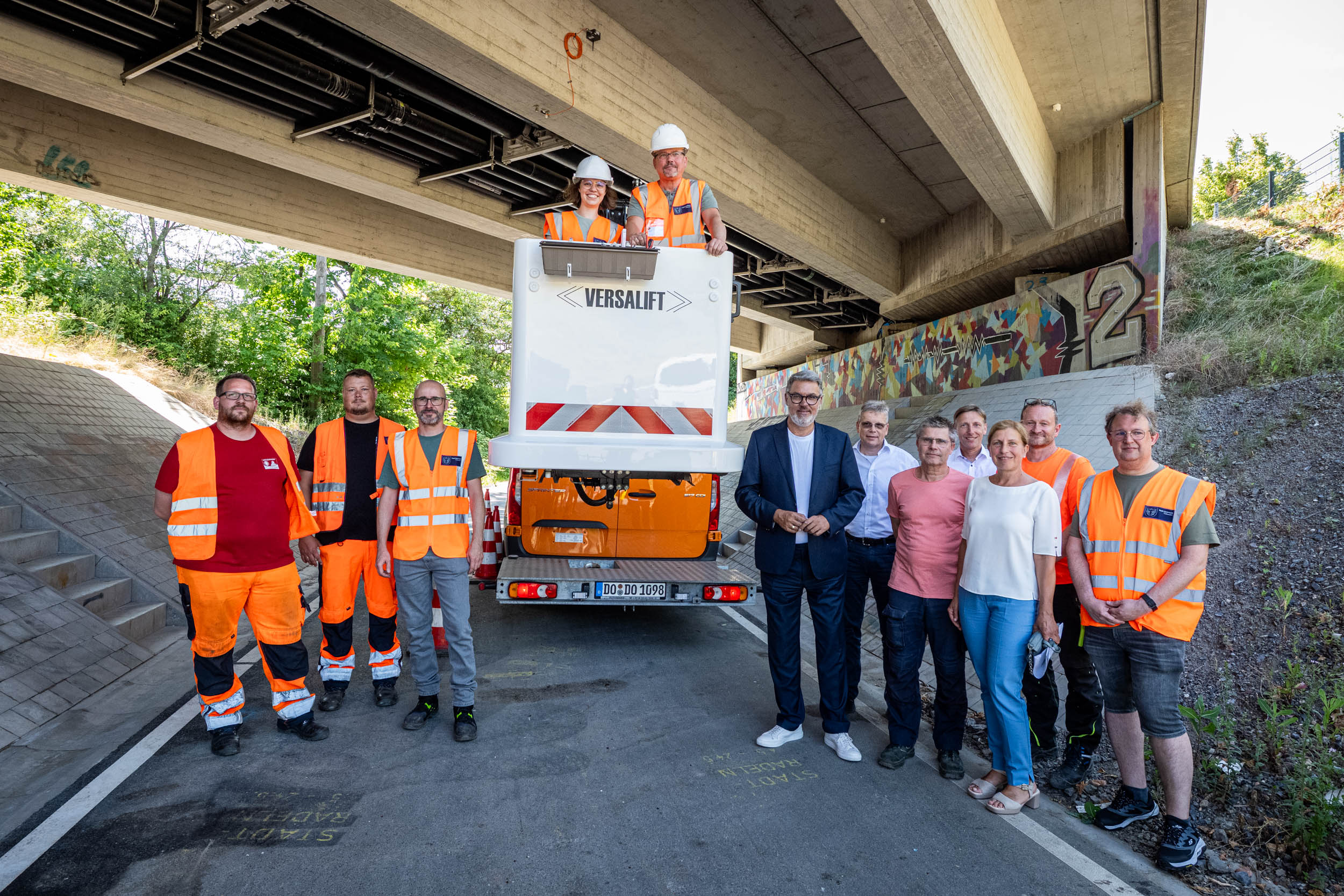 Mehere Personen stehen unter einer Brücke versammelt.