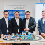 Vier Personen stehen hinter einem Legomodell.