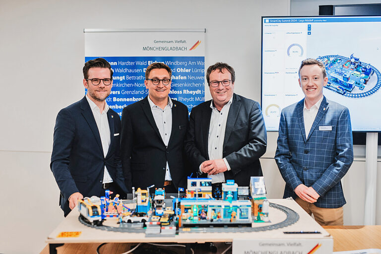 Vier Personen stehen hinter einem Legomodell.