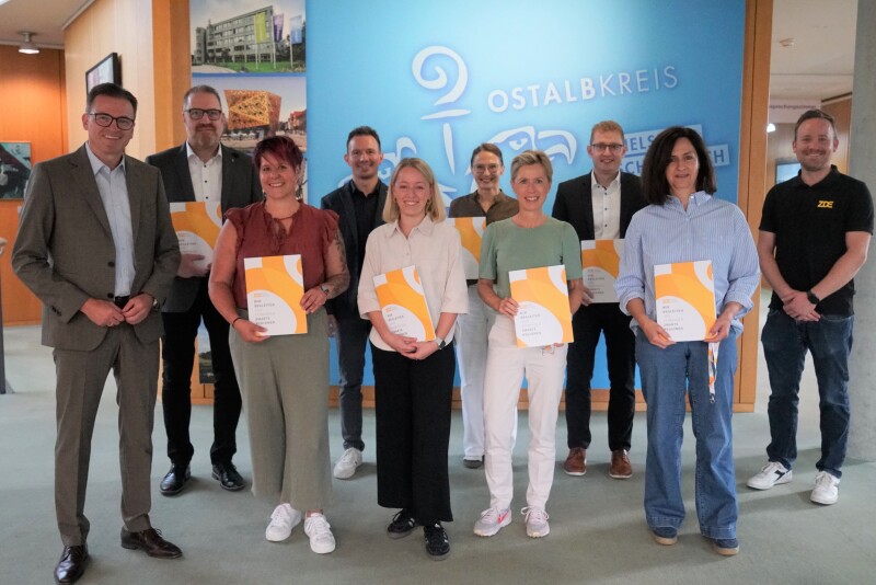 Mehrere Personen stehen nebeneinander, einige halten eine Urkunde in der Hand. Im Hintergrund ist der Schriftzug Ostalbkreis zu sehen.