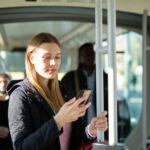 Eine Frau steht in einem Bus und schaut in ihr Smartphone