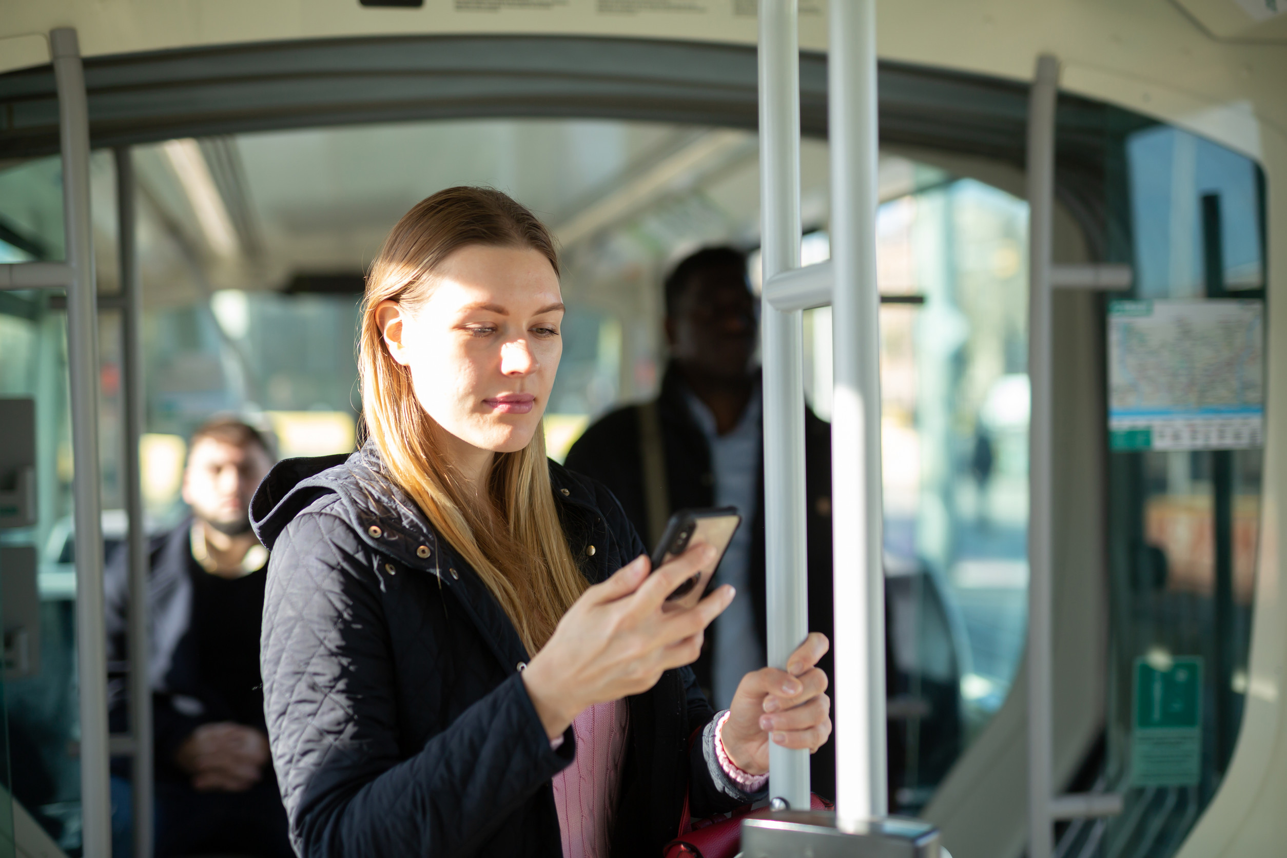 Eine Frau steht in einem Bus und schaut in ihr Smartphone