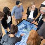 Mehrere Personen stehen um einen digitalen Stadtplan versammelt.