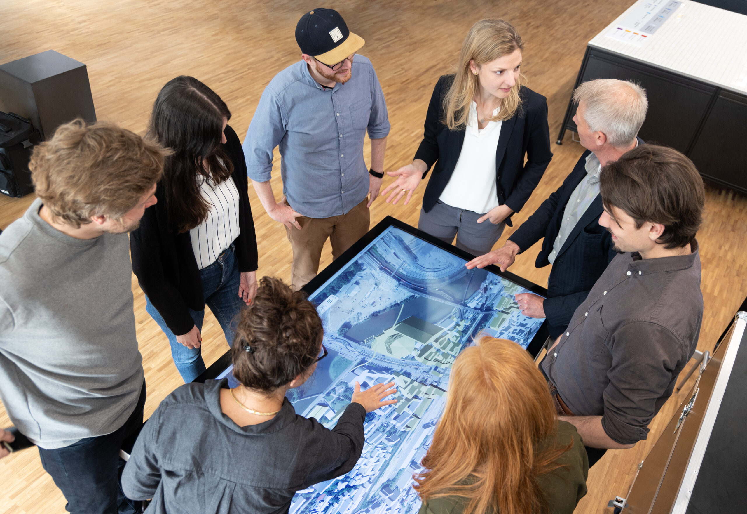 Mehrere Personen stehen um einen digitalen Stadtplan versammelt.