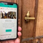 Eine Hand hält ein Smartphone auf dessen Bildschirm die Startseite der Osnabrück-App zu sehen ist.