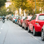 Viele Autos parken neben einer städtischen Straße.
