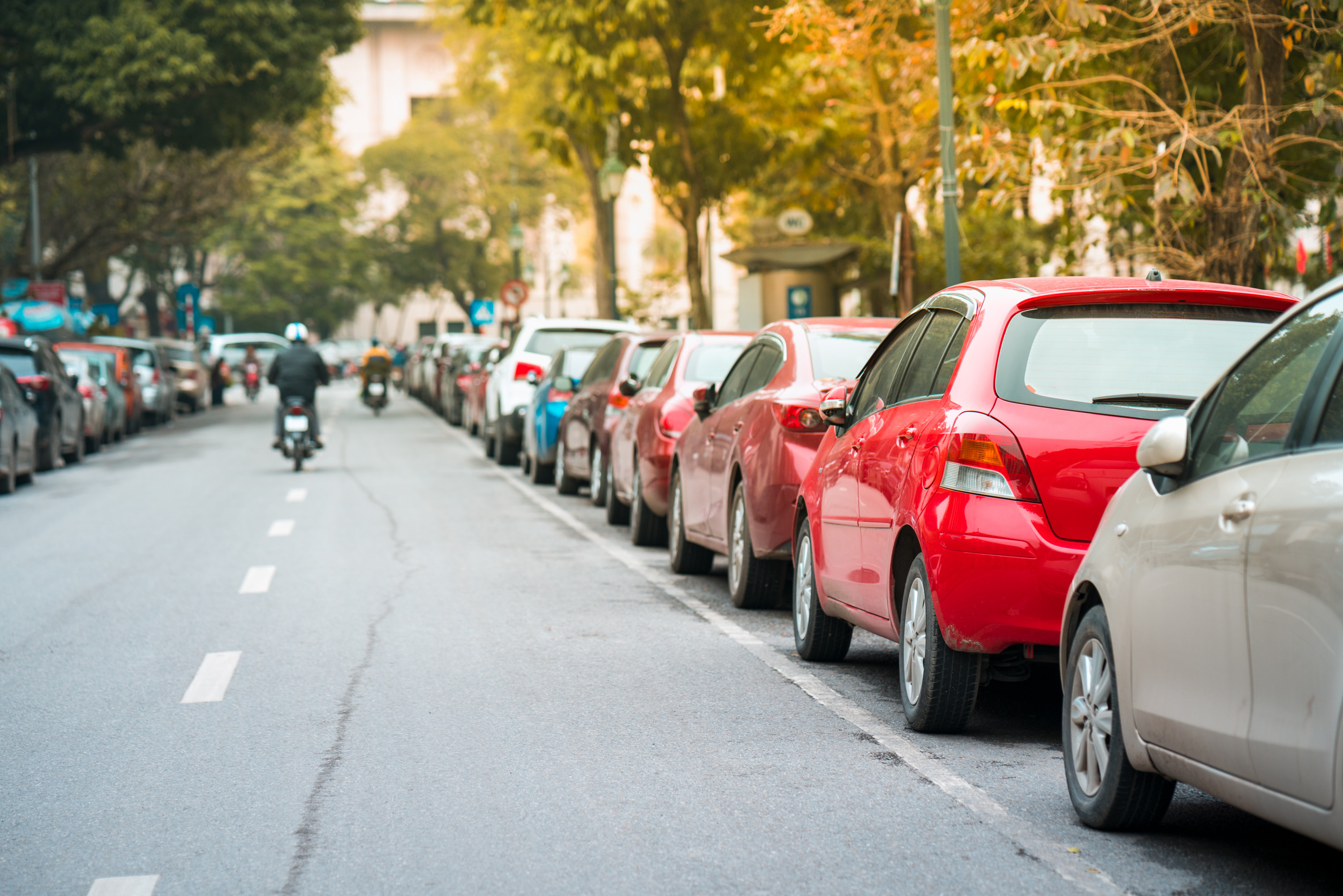 Viele Autos parken neben einer städtischen Straße.