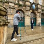 Ein Mann filmt eine junge Frau vor dem Kasseler Rathaus.