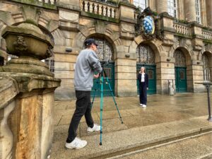 Ein Mann filmt eine junge Frau vor dem Kasseler Rathaus.