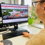 Eine Frau sitzt vor einem Monitor, auf dem Bildschirm ist das Serviceportal der Stadt Oldenburg zu sehen