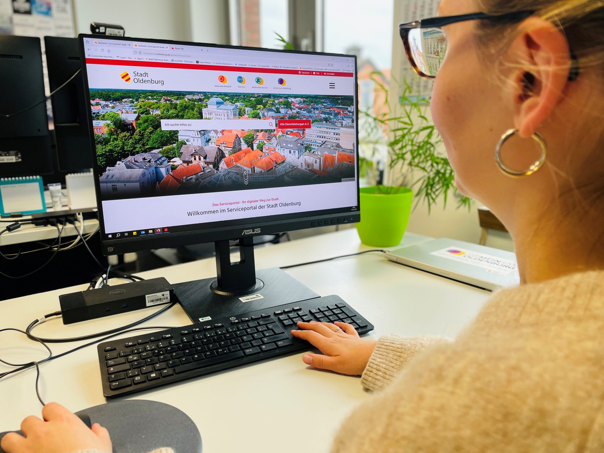 Eine Frau sitzt vor einem Monitor, auf dem Bildschirm ist das Serviceportal der Stadt Oldenburg zu sehen