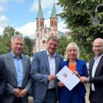 Mehrere Personen stehen nebeneinander, während Ministerin Sinemus ein Dokument überreicht.