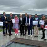 Mehrere Personen stehen nebeneinander und halten Dokumente in der Hand.