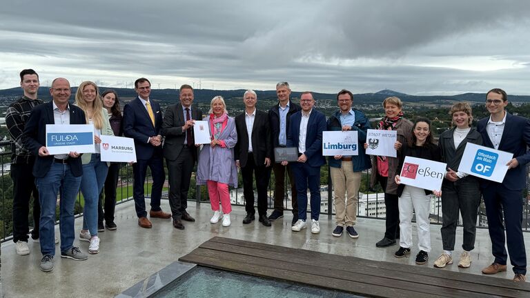Mehrere Personen stehen nebeneinander und halten Dokumente in der Hand.