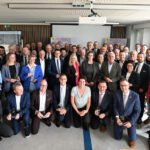 Eine größere Personengruppe steht für ein Foto versammelt im Halbkreis.