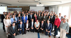 Eine größere Personengruppe steht für ein Foto versammelt im Halbkreis.