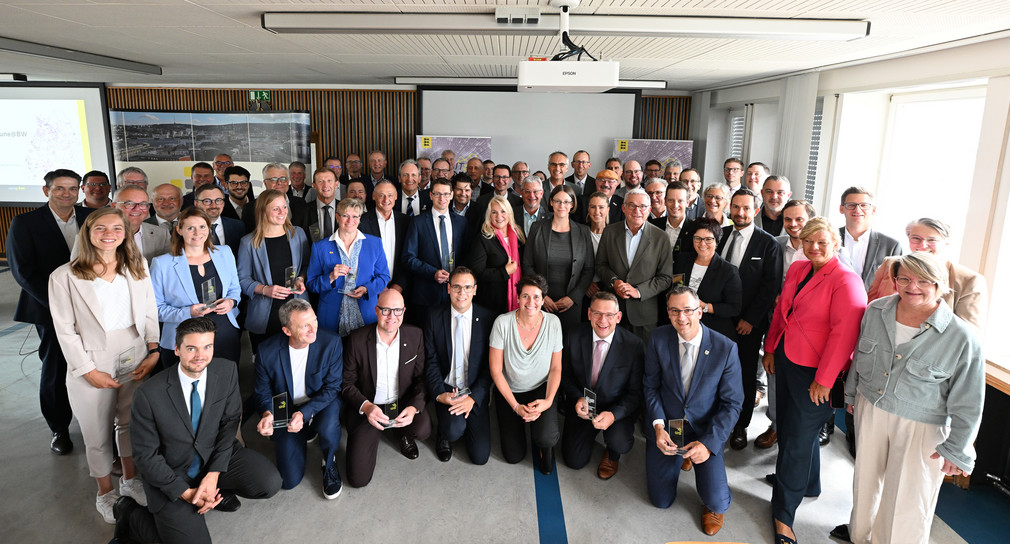 Eine größere Personengruppe steht für ein Foto versammelt im Halbkreis.