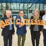 Vier Personen halten einen 3D-Schriftzug "Smart City Essen" hoch.