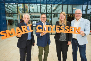 Vier Personen halten einen 3D-Schriftzug "Smart City Essen" hoch.