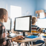 Schüler arbeiten in einem Klassenzimmer mit Computern.