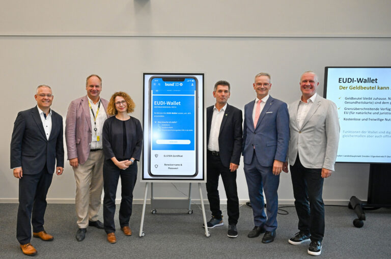 Sechs Personen vor einem Aufsteller zum Start des Pilotprojekts zur EUDI-Wallet in Dresden