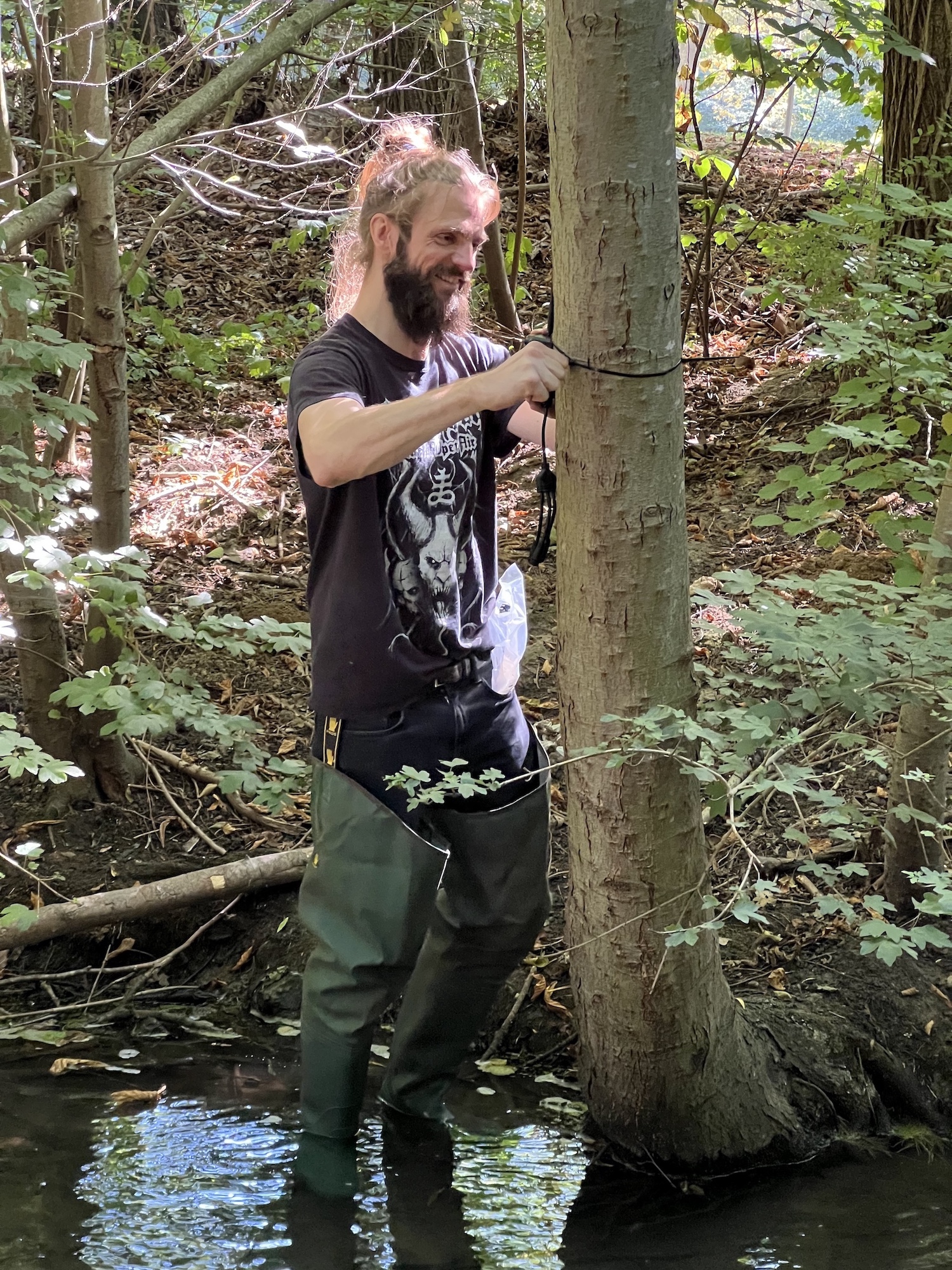 Ein Mann befestigt etwas an einem Baum.